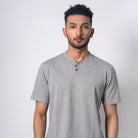 Man wearing a gray henley shirt against a white background