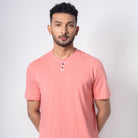 Man wearing a pink henley shirt against a white background