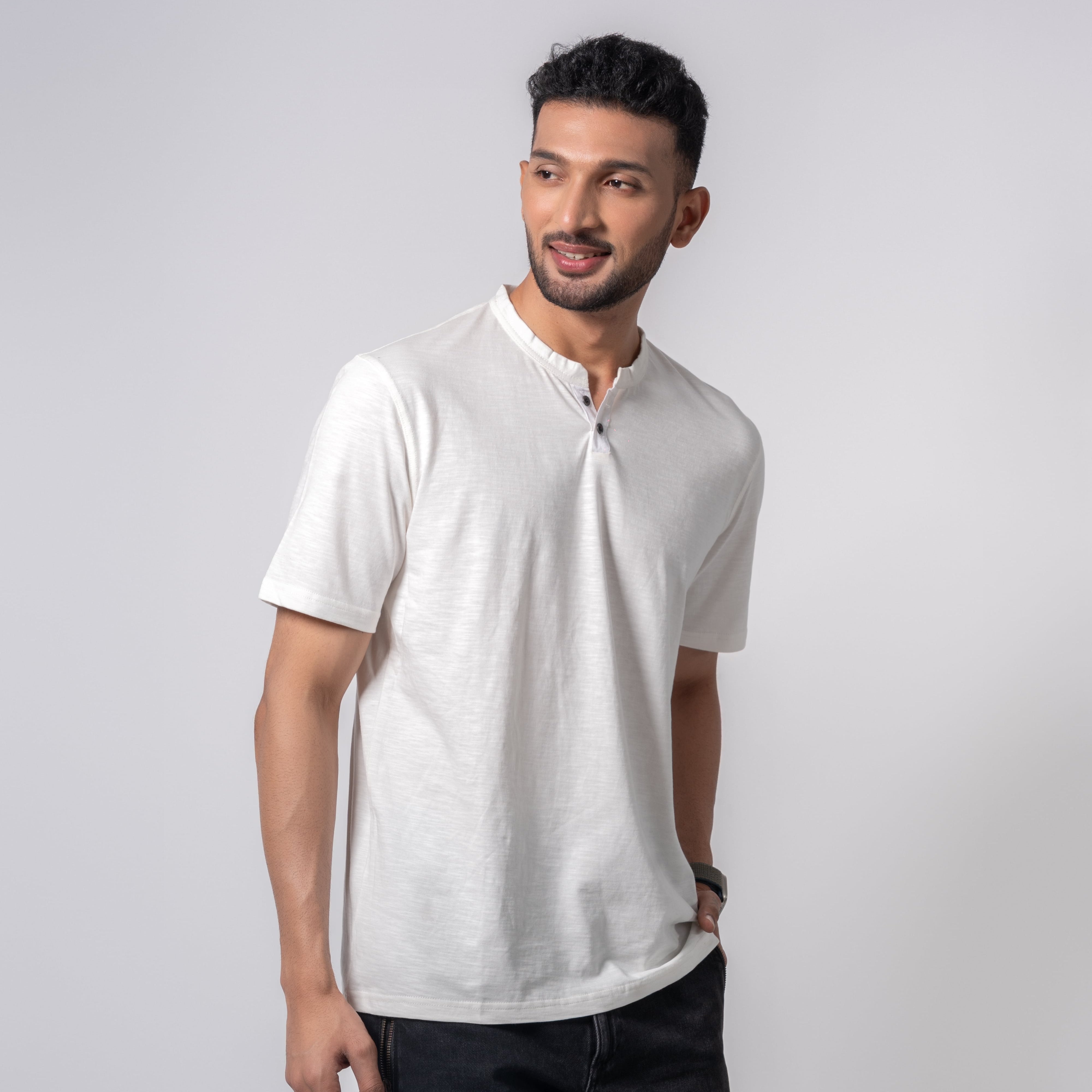 Man wearing a white shirt and dark pants on a light gray background