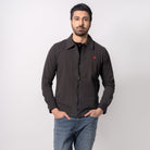 Man wearing a dark jacket with a red logo, blue jeans, and white sneakers on a white background