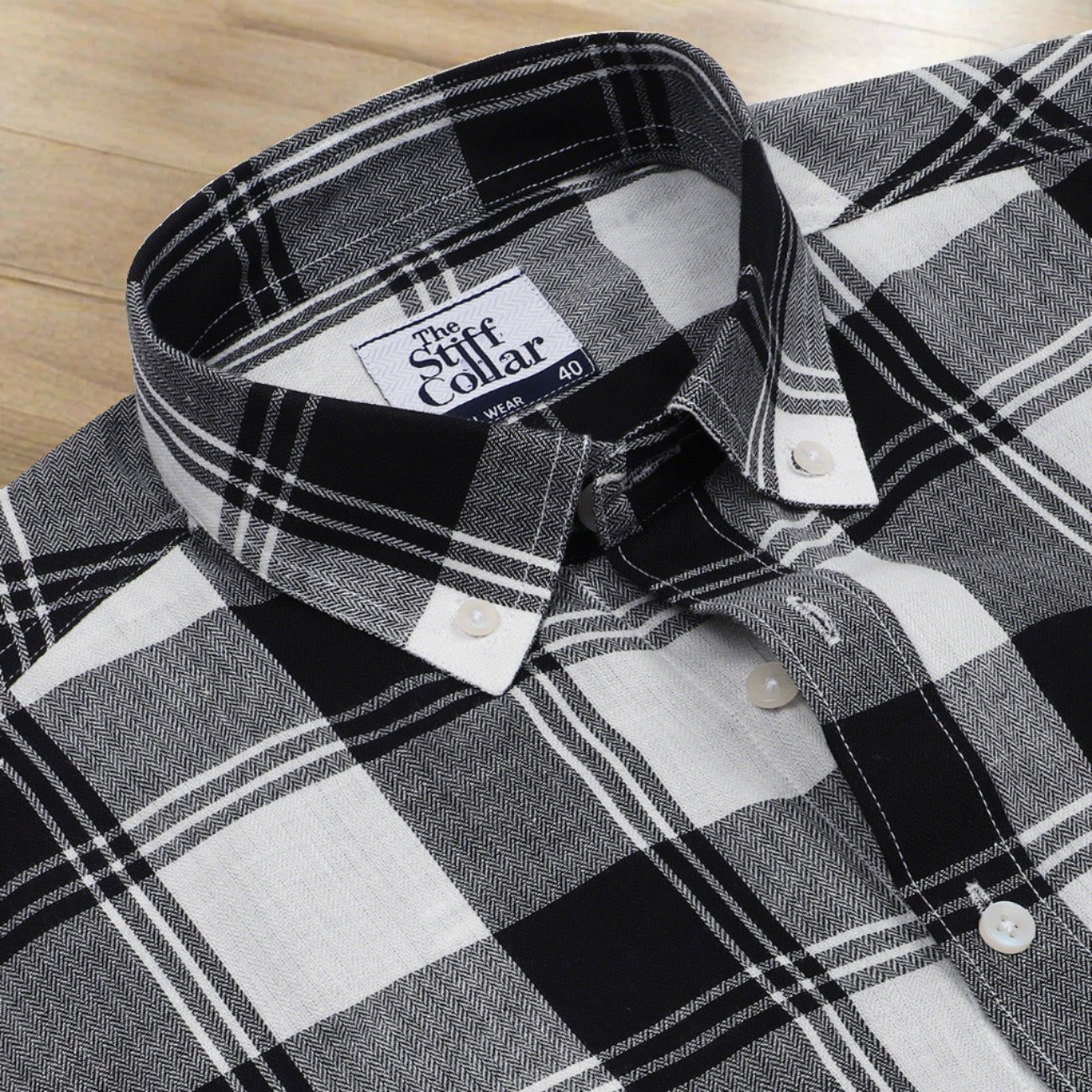 Two button-up shirts side by side, one white and one black, with a checkered pattern of squares in varying sizes.